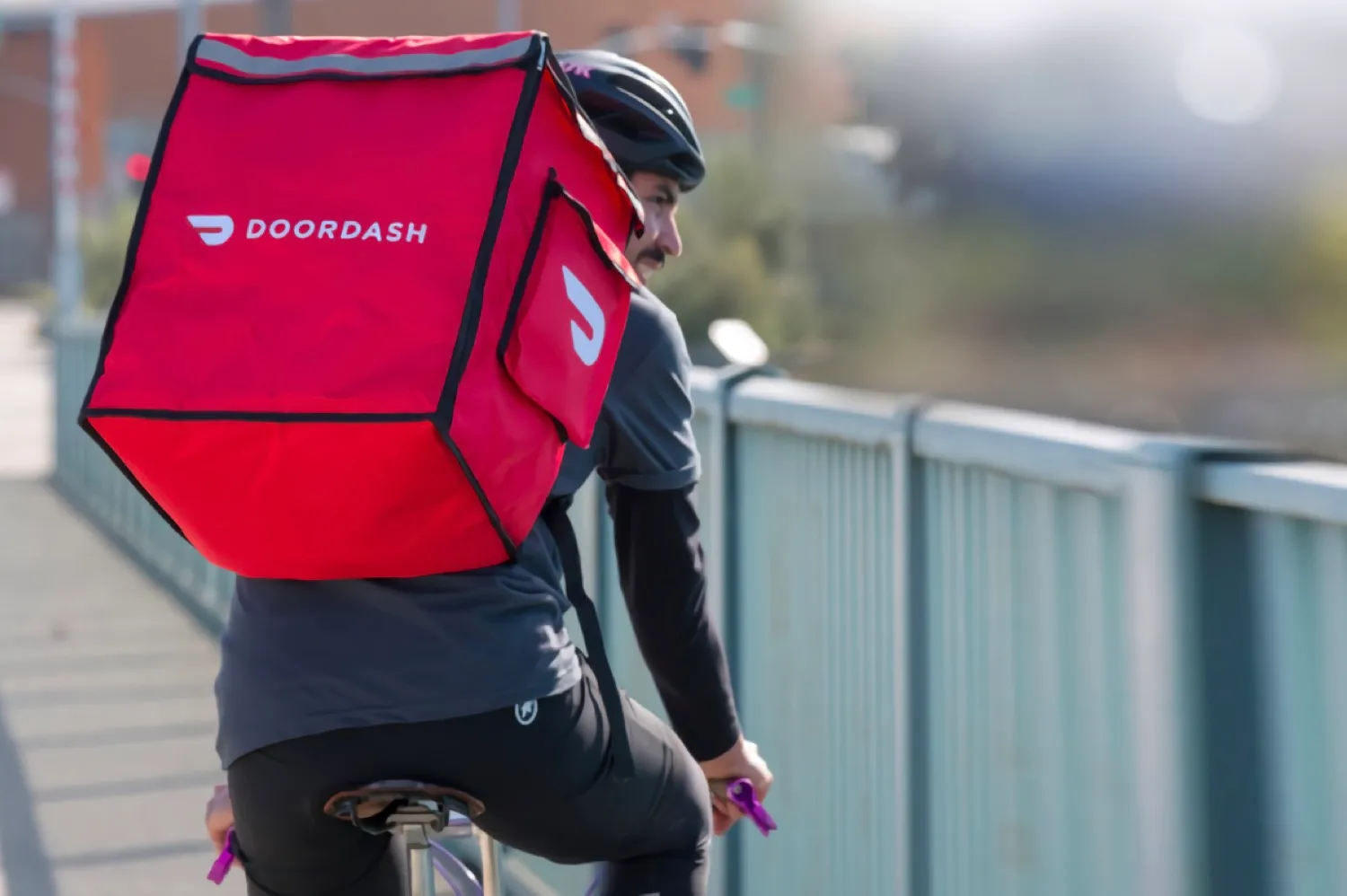 DoorDash delivery driver on bicycle with branded delivery bag for comparison with ChowNow direct ordering