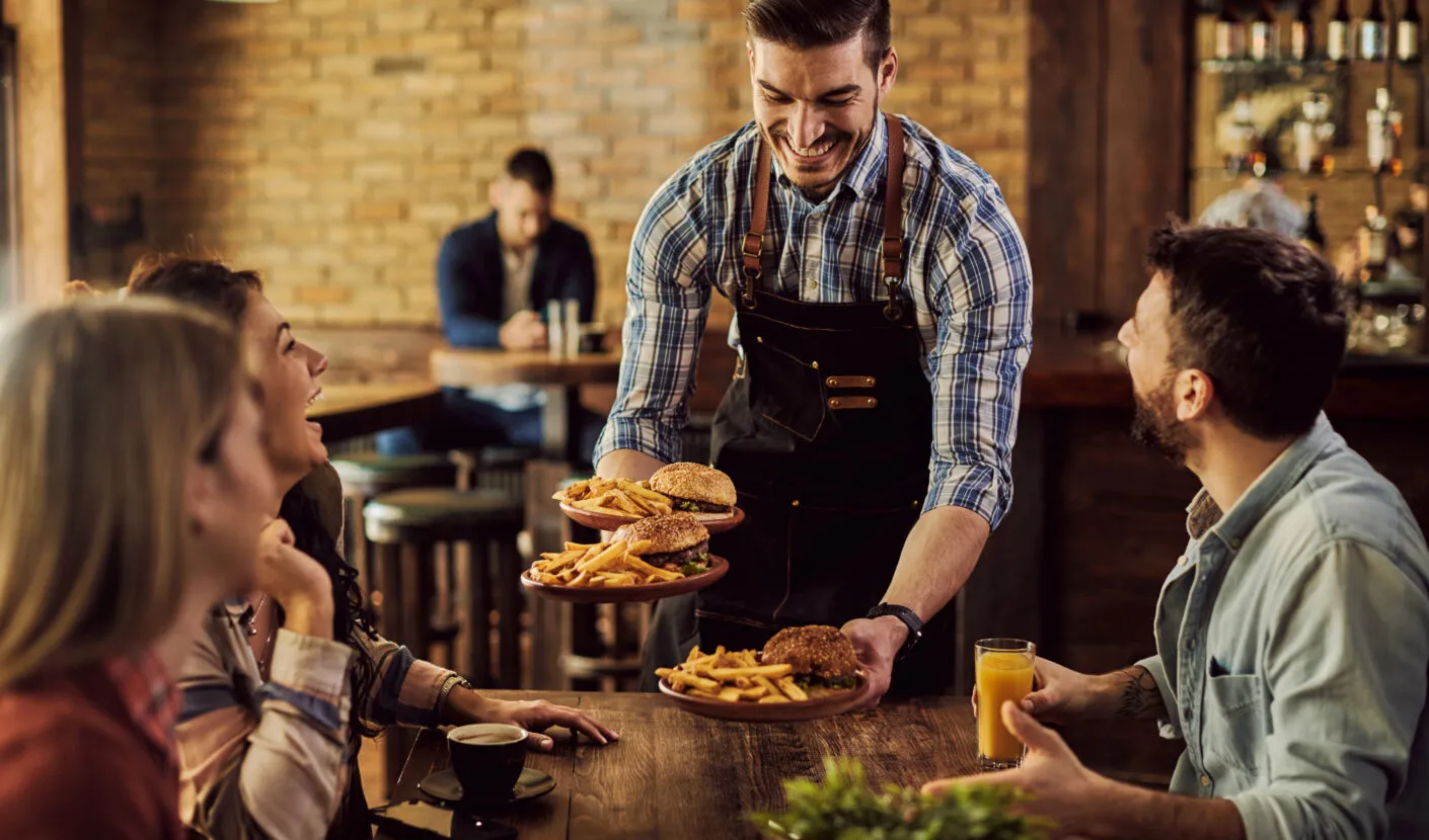 Restaurant server delivering burgers and fries to happy customers at an independent restaurant